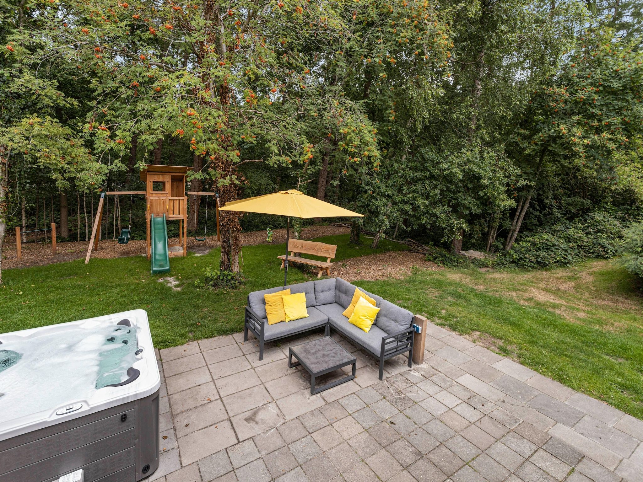 Het terras van 20 pers groot Abeltjeshuis Wellness de luxe met buitenspa in Vlagtwedde